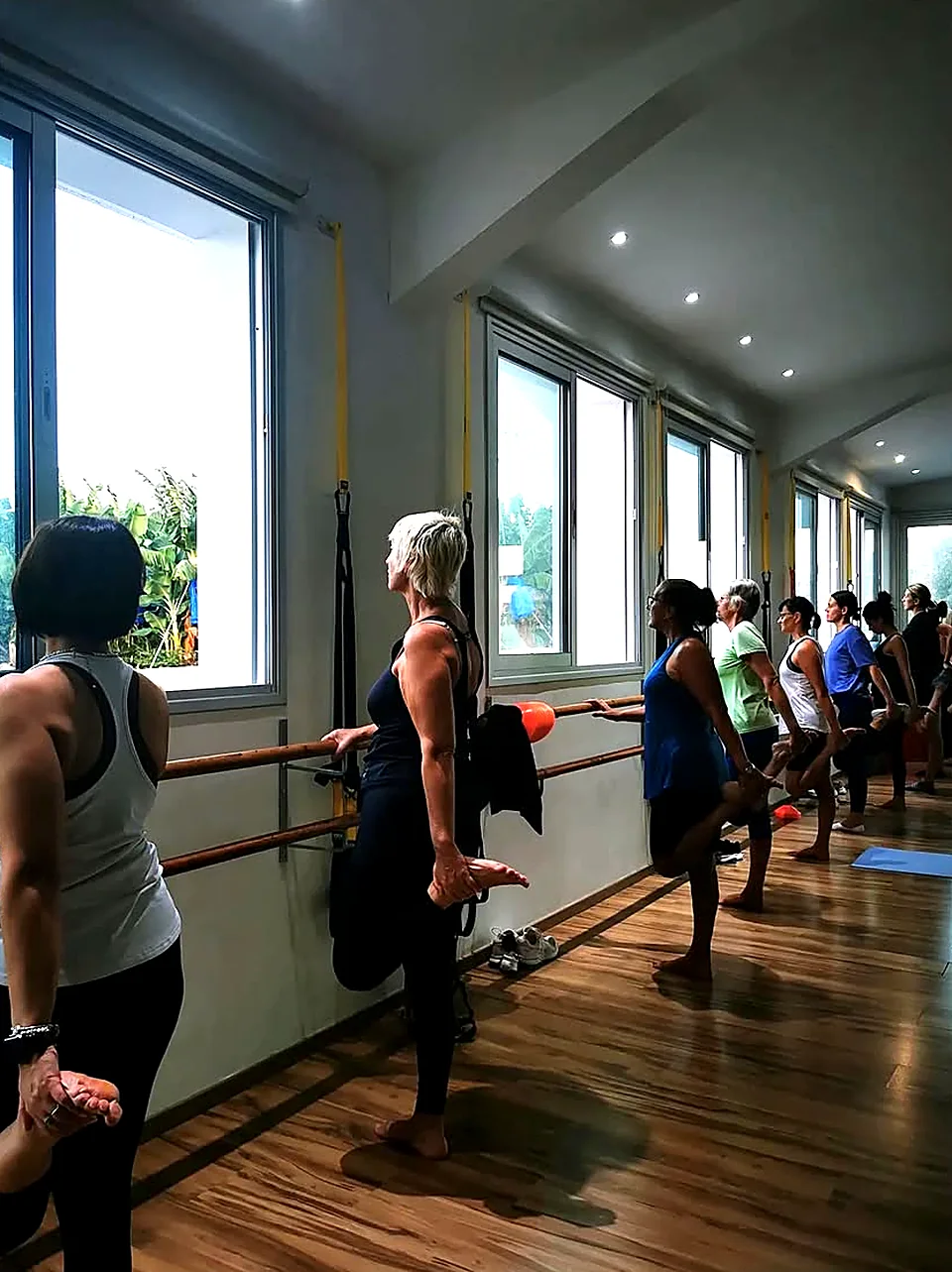 Women balancing at the ballet bar during a barre workout class at Rewell Emotion Fitness, Peyia