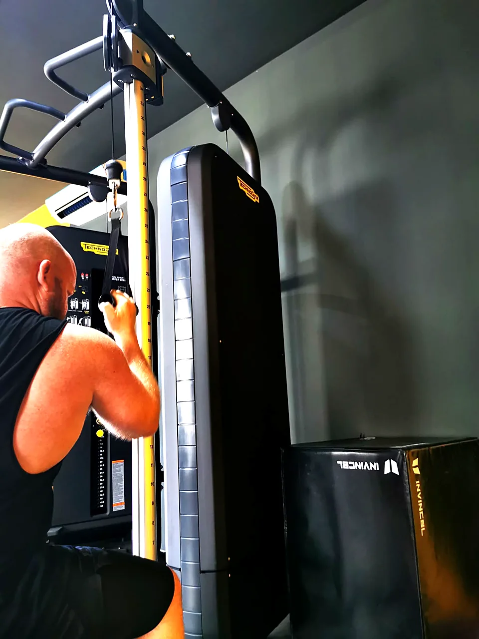 Man training on a Technogym cable machine in the strength area of a gym in Peyia