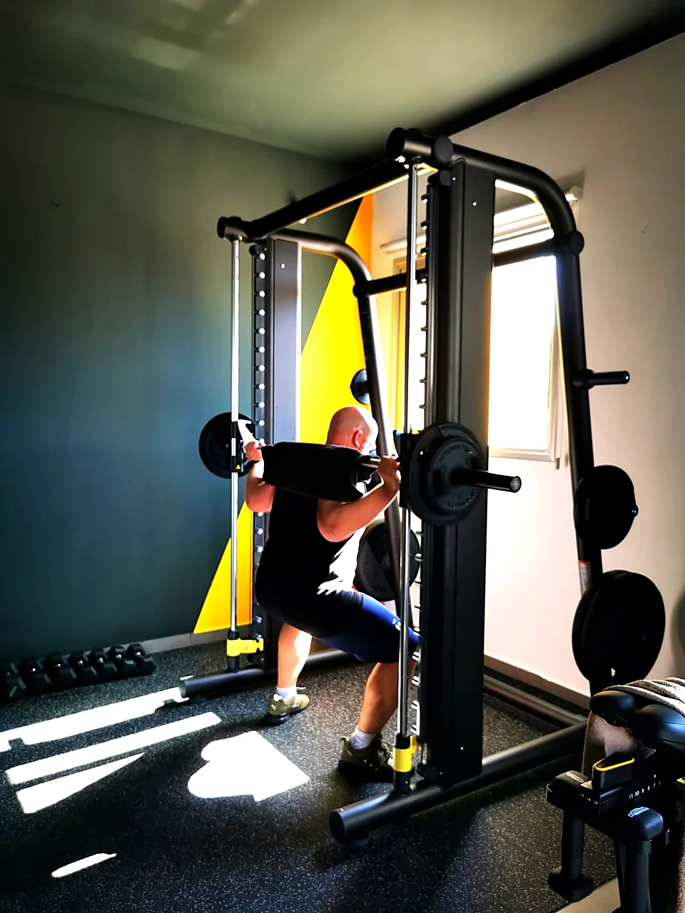 Man squatting in a Smith machine during personal training at a gym in Peyia