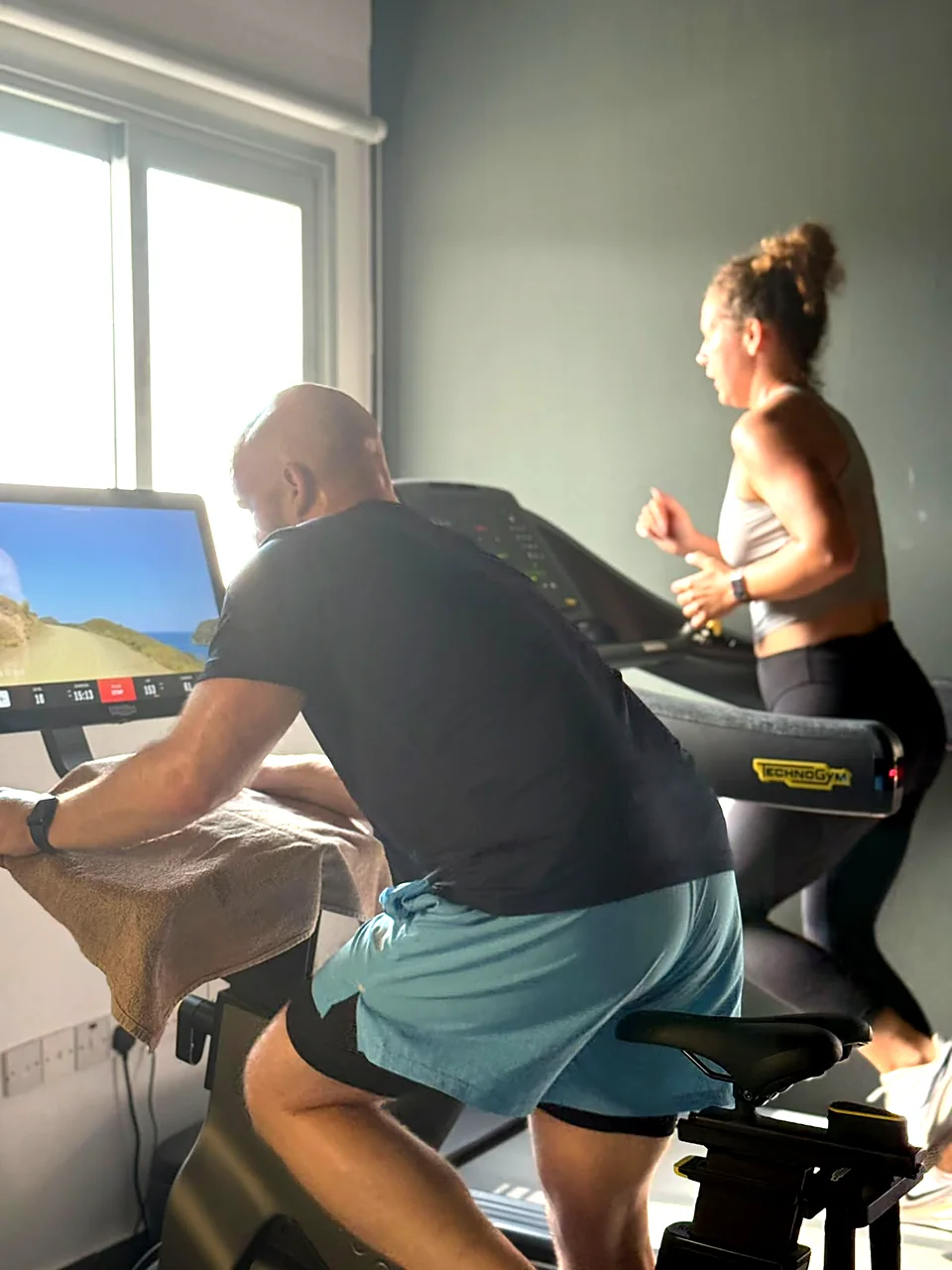 Members training on a Technogym bike and treadmill in the cardio area of the gym in Peyia